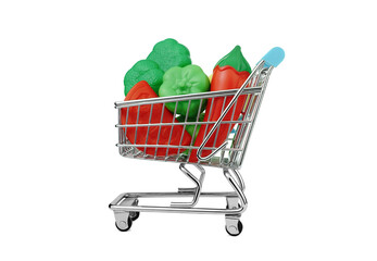 Mini shopping cart with plastic toy vegetables isolated on white background.