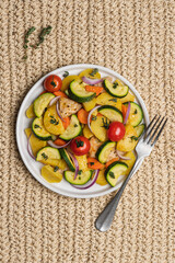 Baked vegetables and meat in plate on wicker background. Cooked dish of Potatoes, zucchini, carrots, onions, tomato and chicken