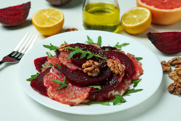 Plate of tasty beet salad and ingredients on white background