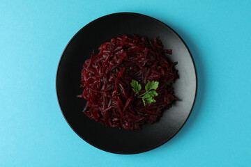Plate with fresh beet salad on blue background, top view
