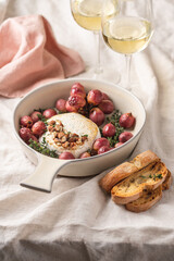 Baked camembert cheese with grapes, nuts, honey and thyme. White food background