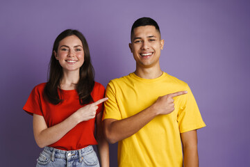 Fototapeta premium Brunette joyful couple smiling and pointing finger aside