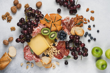 Cheese, slicing salami, ham, grapes, nuts and fruits on marble board. Party snacks.  Wine snacks on white background, top view 