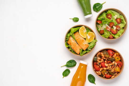 Paper containers with healthy takeaway food. Salmon, lettuce and bell peppers with beans. Bottled smoothies or juice.  Food delivery concept