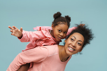Joyful black mother and daughter with butterfly wings doing piggyback ride