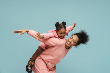 Joyful black mother and daughter with butterfly wings doing piggyback ride