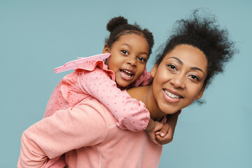 Joyful black mother and daughter with butterfly wings doing piggyback ride