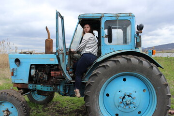 The girl on the tractor in the field. Plow the