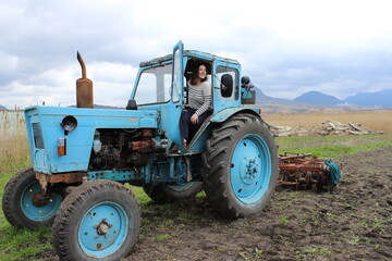 The girl on the tractor in the field. Plow the
