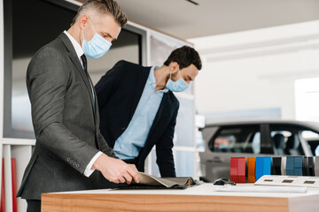 Mid unshaven manager working with mature customer in car showroom