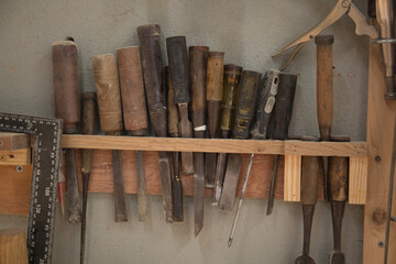 A rack full of chisel and handtools for wood carving in a workshop 