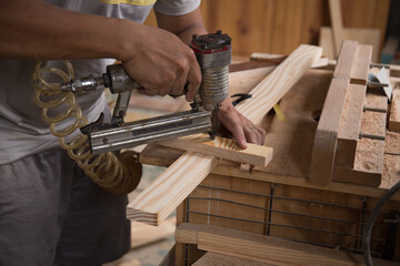 Closeup of a man carpenter using a nail gun.
