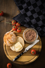 Grobe Leberwurst im Glas aus Vorrat mit Brötchen, Butter und Tomaten als Vesper Brotzeit auf...