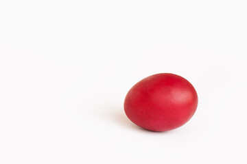 Close-up painted red egg settled in the middle of white background. Easter concept, copy space for text.