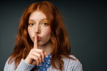Young ginger white woman showing silence gesture at camera