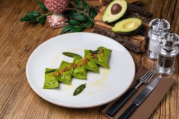 Green dumplings with spinach and sauce on a large white plate

