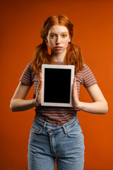 Ginger young woman with tails showing tablet pc at camera