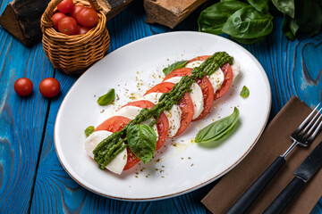 Mozzarella, tomatoes, basil sauce on a white plate
