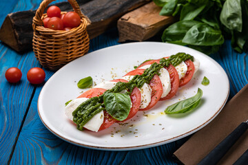 Fototapeta na wymiar Mozzarella, tomatoes, basil sauce on a white plate 