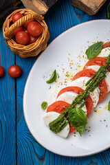 Mozzarella, tomatoes, basil sauce on a white plate
