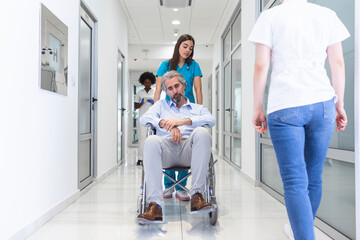 Wheelchair patient with professional female doctor and nurse specialist staff in corridor of hospital recovery center