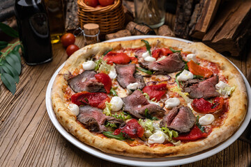 Pizza with tomatoes, meat, soft cheese and herbs
