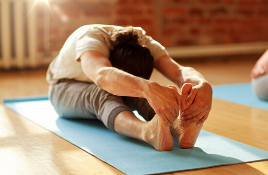 man doing yoga forward bend at studio or gym