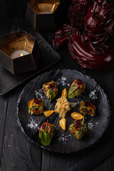Japanese rolls on a dark plate in a restaurant
