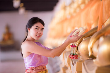 The girl in Thai dress presents a garland for the Lord Buddha.preserving the good culture of Thai people during Songkran festival. Thai New Year, Family Day in April