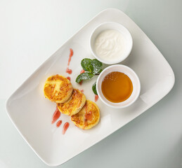 Cheesecakes with sour cream and honey on a white table
