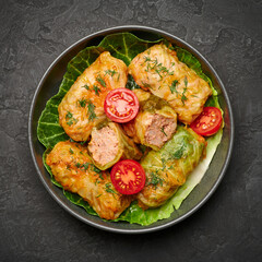 Golubtsi or golabki on black bowl on dark slate table top. Stuffed cabbage rolls dish of russian, polish, ukrainian cuisine. European food.
