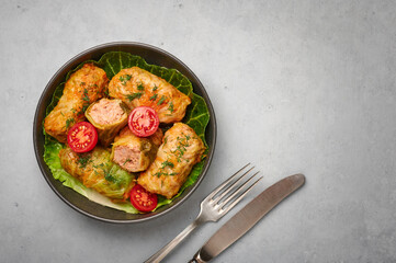 Golubtsi or golabki on black bowl on concrete table top. Stuffed cabbage rolls dish of russian,...