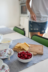 family early breakfast in a white kitchen with cheese with tea and berries