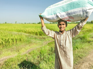 a young Asian boy is carrying a heavy lot of full of goods