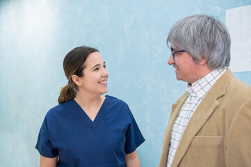 Young, smiling woman doctor chatting with middle-aged patient in dental clinic