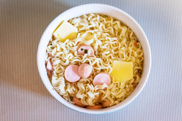 Noodles with cheese and sausages in a close-up bowl