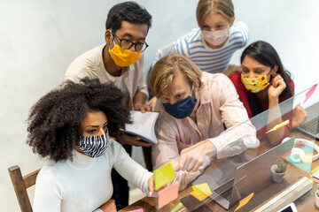 multiracial group of university students working at project, social distancing and prevention wearing face masks, teamwork collaboration concept during outbreak of Corona Virus