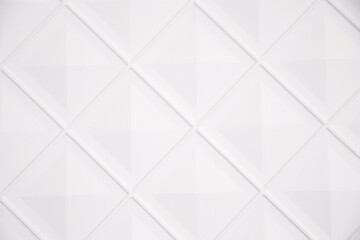 White wall decorated with diamonds. Geometric shapes in the interior. Stylish and voluminous background.