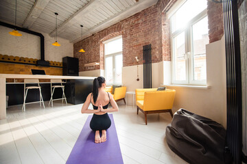 Woman meditating on yoga mat by joining hands behind back
