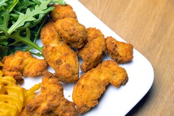 Chicken nuggets with salad on table closeup