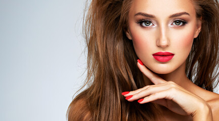 Face of young woman with red nails, lipstick and long brown hair.   Model with fashion makeup.