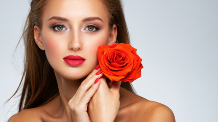 Beautiful young woman with a red flower in hand near face.  Portrait of a  girl with red rose in hands
