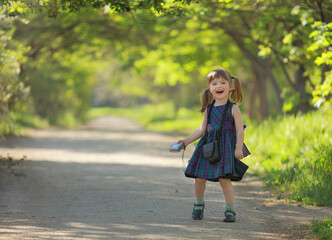 a little girl photographer with long hair is standing on the road  in her hand and a camera, smiling, laughs. green background. copy space.