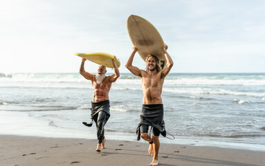 Happy friends with different age surfing together - Sporty people having fun during vacation surf...