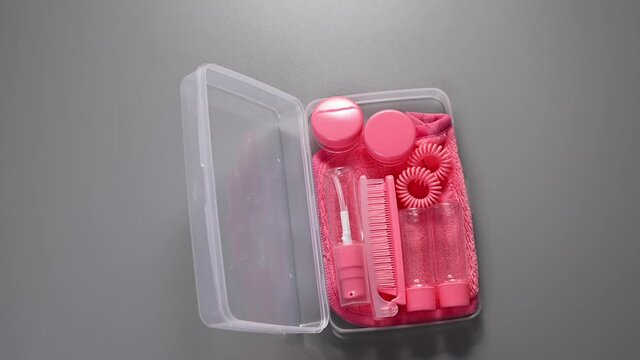 Travel kit. Small plastic jars, face and hair accessories for travel pink. Cosmetic bag with miniatures for cosmetics. Stop Motion. Copy space. High quality FullHD footage
