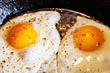 Roasted eggs in a frying pan with seasoning for breakfast.