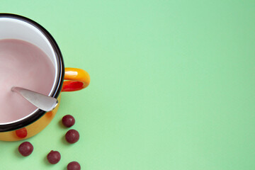 Iron orange cup with cocoa and chocolate balls on green background. Flat lay. Selective focus