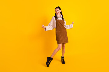 Full size photo of nice brunette optimistic curly hairdo lady dance look empty space wear sweater overall shoes isolated on yellow background