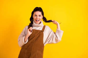 Portrait of attractive cheerful girl posing having fun making tails isolated over bright yellow color background