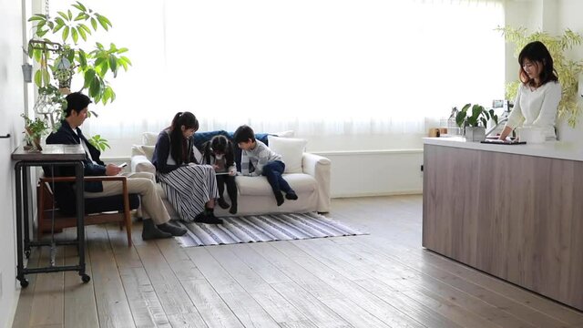 キッチンに立つ母親とリビングでくつろぐ家族